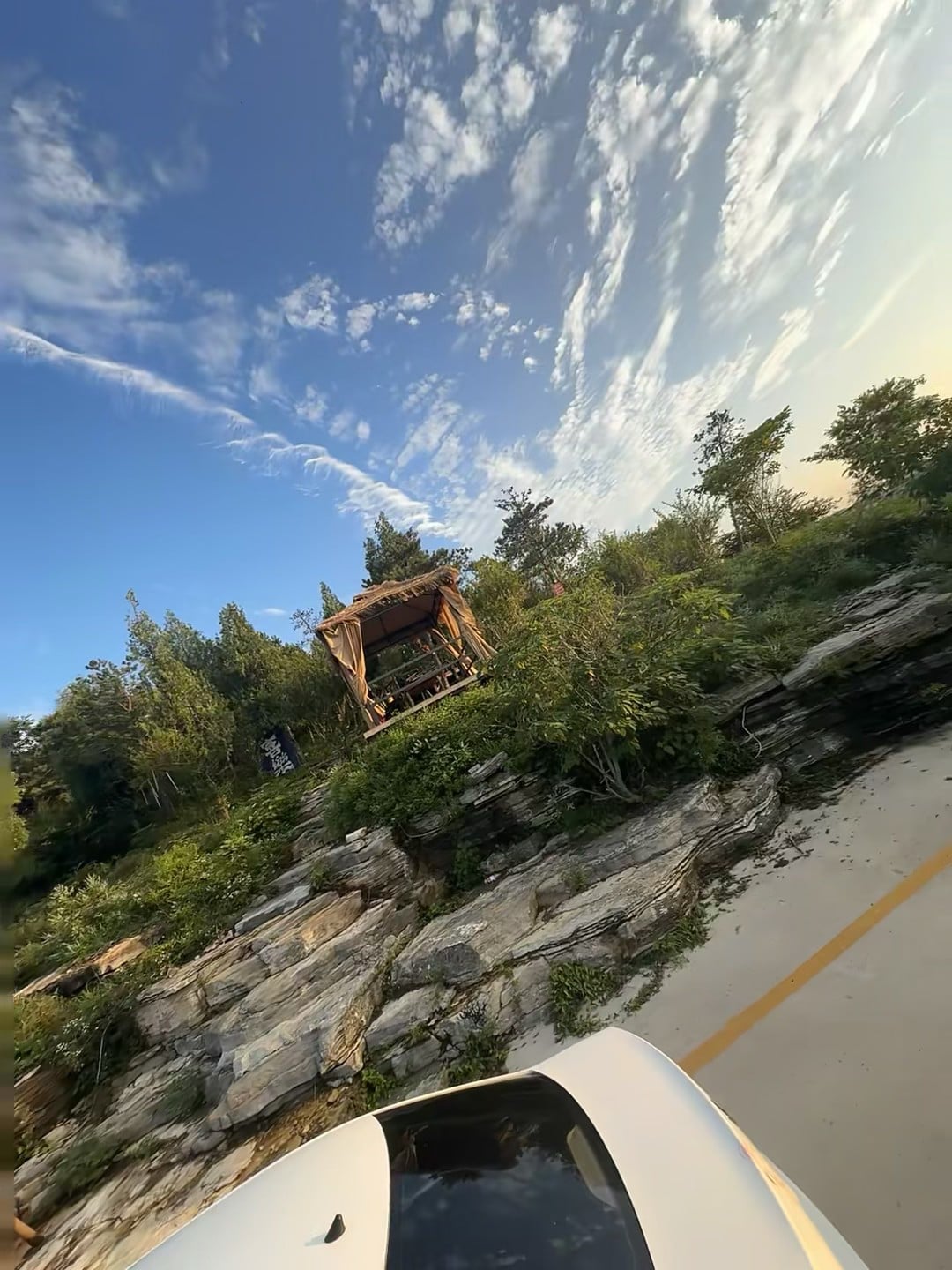 今天在山边小路停了下，车顶刚好框住这顶草棚——蓝天和乱石堆，像被风揉过的旧画