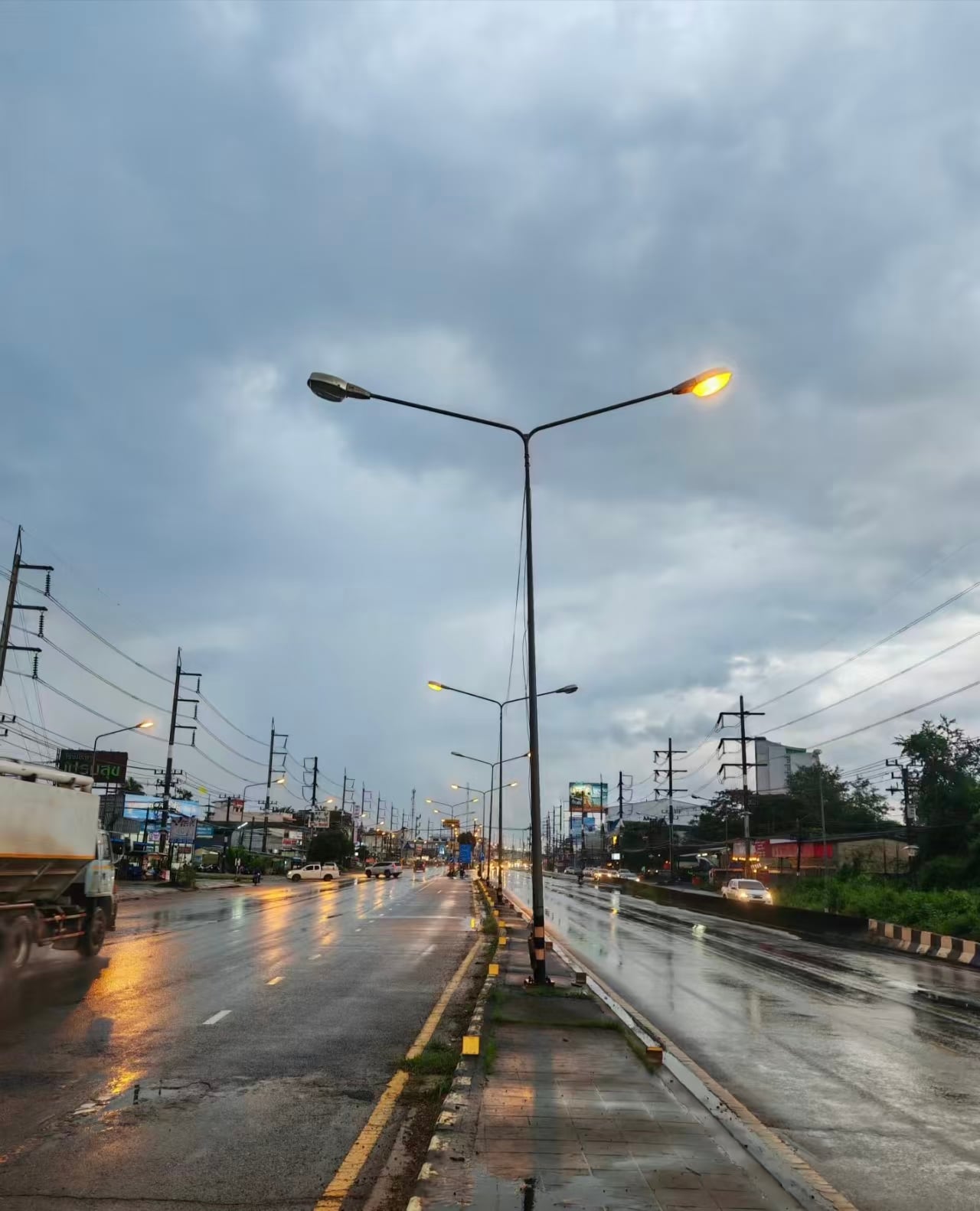 雨后路灯亮起，车灯在湿路上拉长成金线